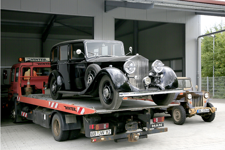 Restaurierter Rolls-Royce auf dem Abschleppwagen vor der Werkstatt von KFZ Winter, daneben ein Willys Jeep.